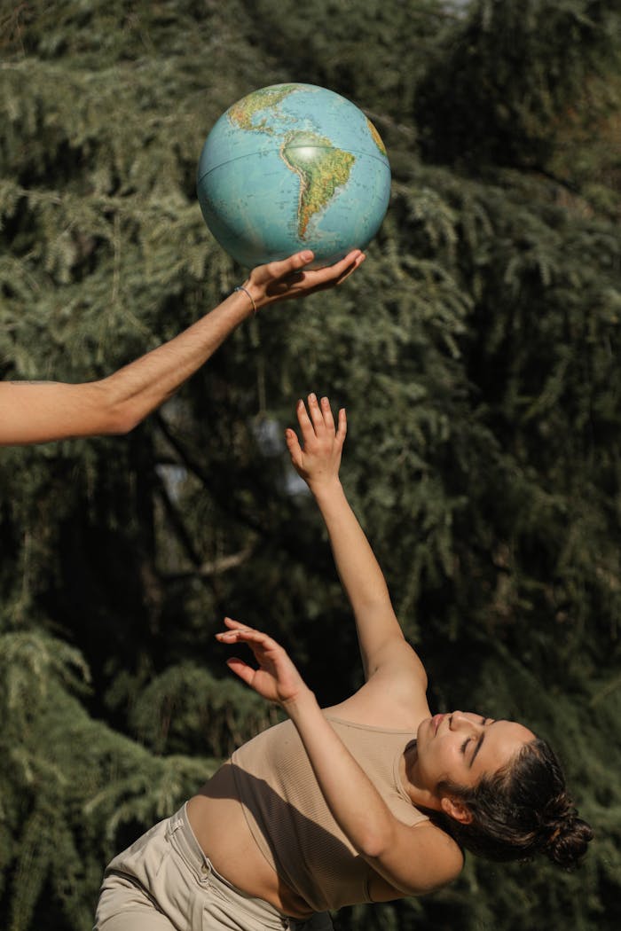 Artistic shot of a woman dancing outdoors with a globe, symbolizing environmental awareness.